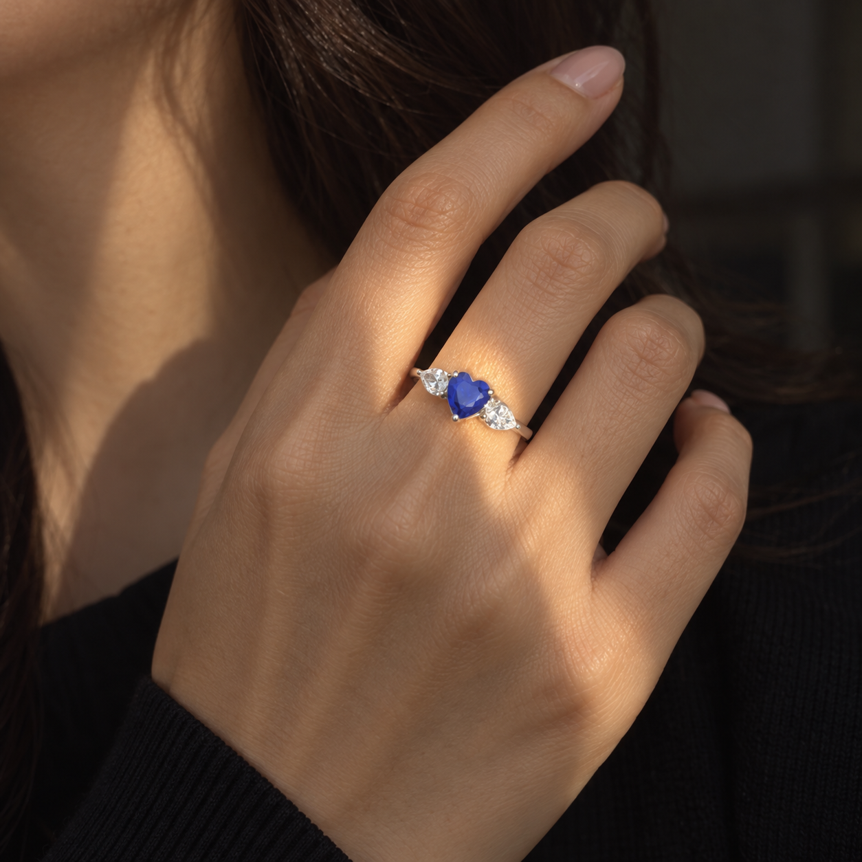 Woman wearing a blue heart-cut CZ three-stone silver ring
